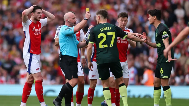 Referee reviewing a VAR decision while players react during a football match